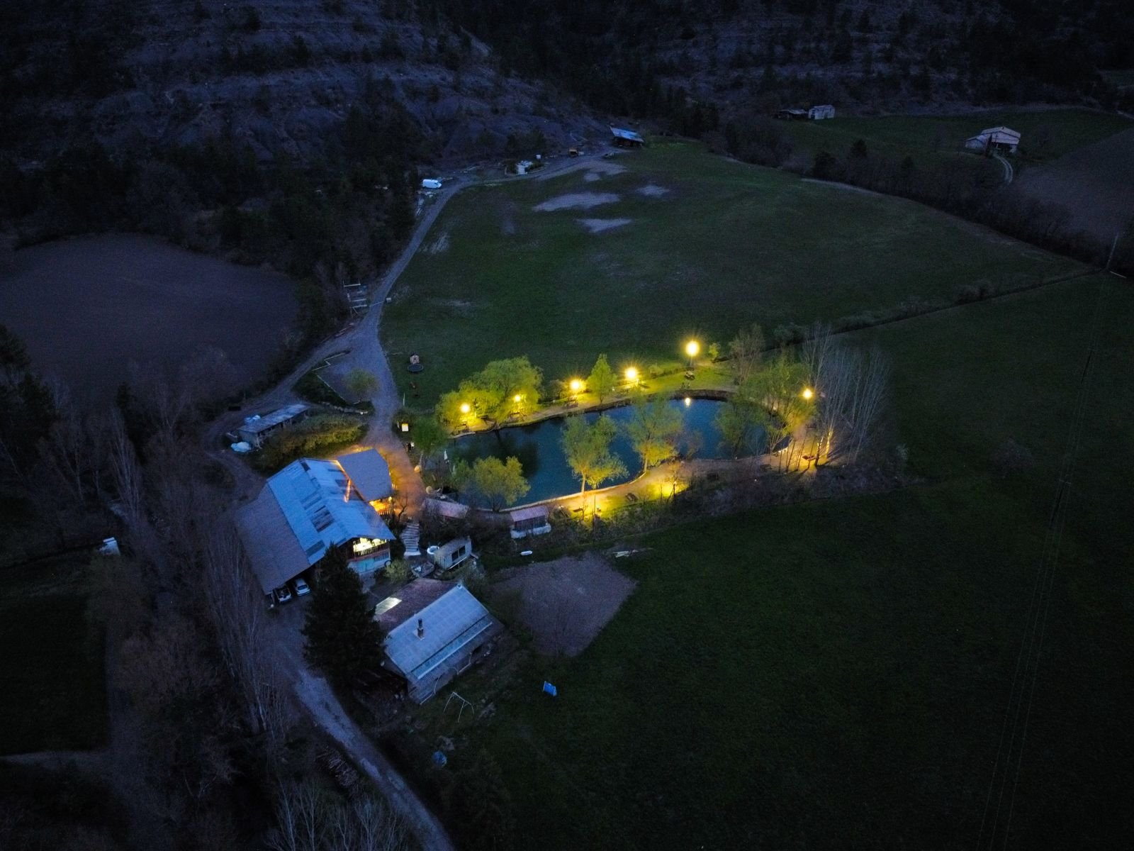 Vue aérienne de la ferme et du lac éclairé à la tombée de la nuit
